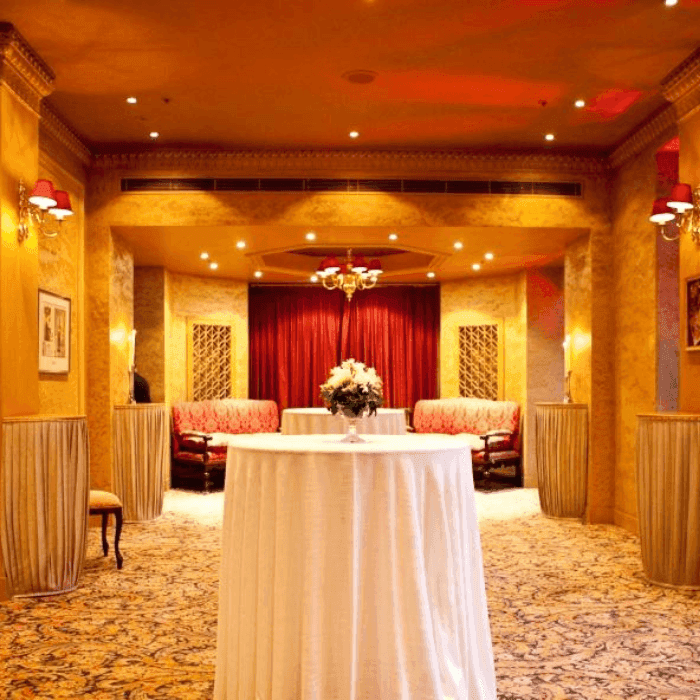 Elegant event space with a white-covered round table and floral centerpiece under warm lighting.