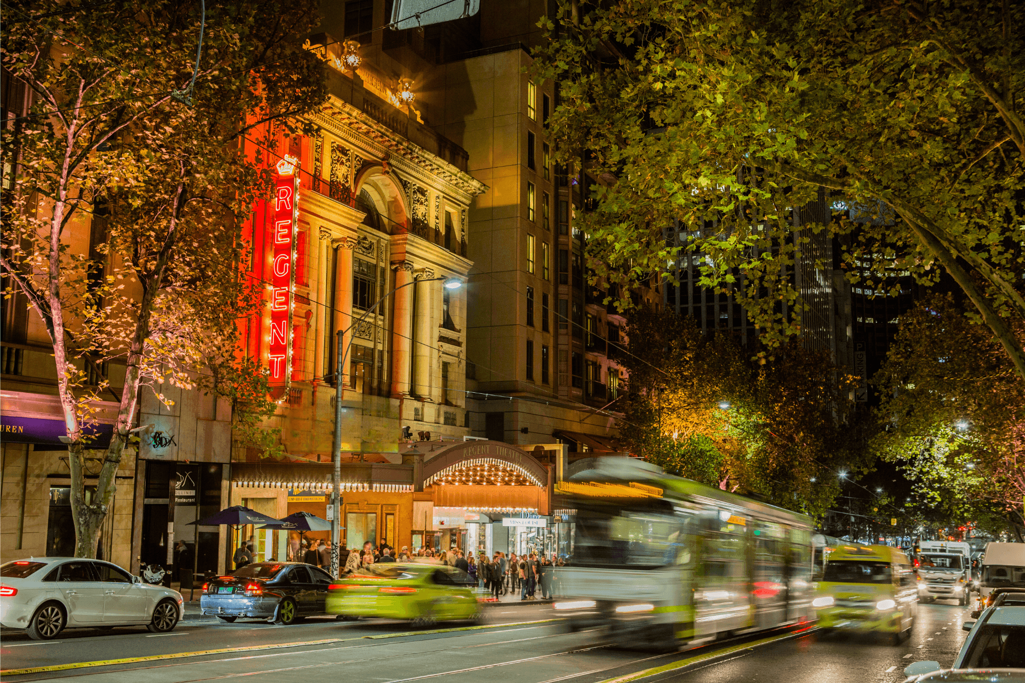 Dynamic night scene of city street with illuminated architecture and blurred vehicles.