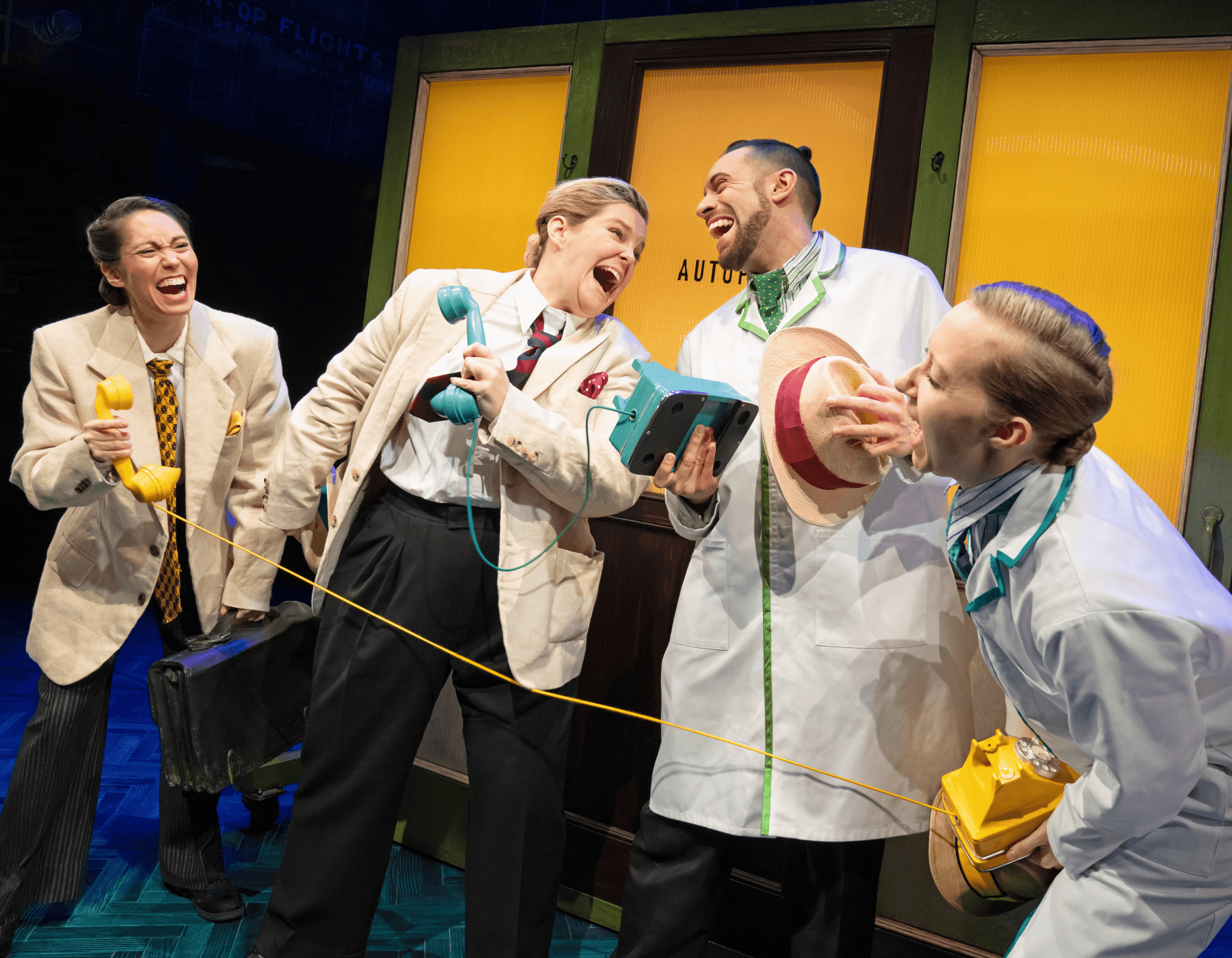 Four animated actors on stage, laughing and interacting with old-fashioned telephones.