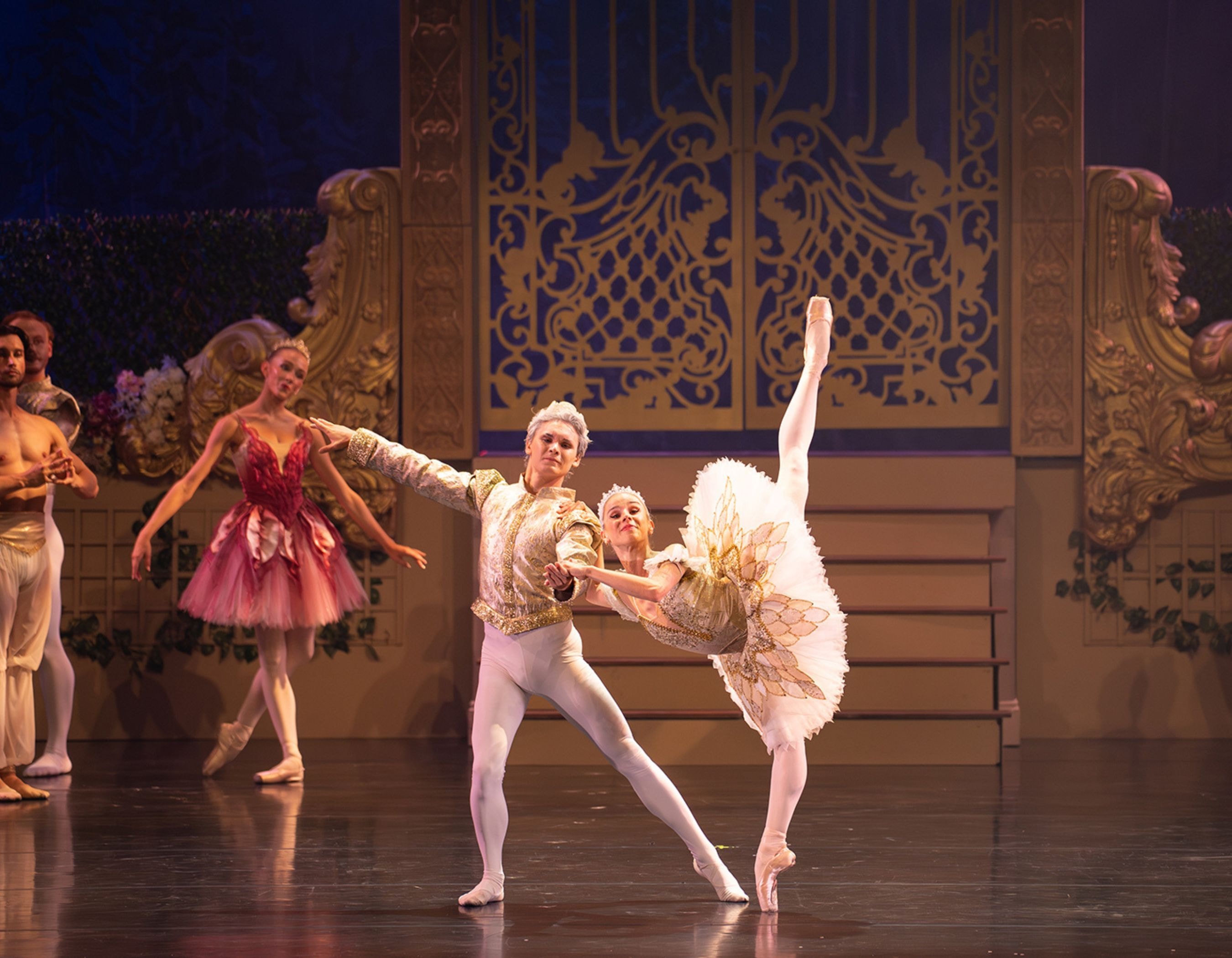 Two ballet dancers in ornate costumes perform gracefully on stage, with the female en pointe.