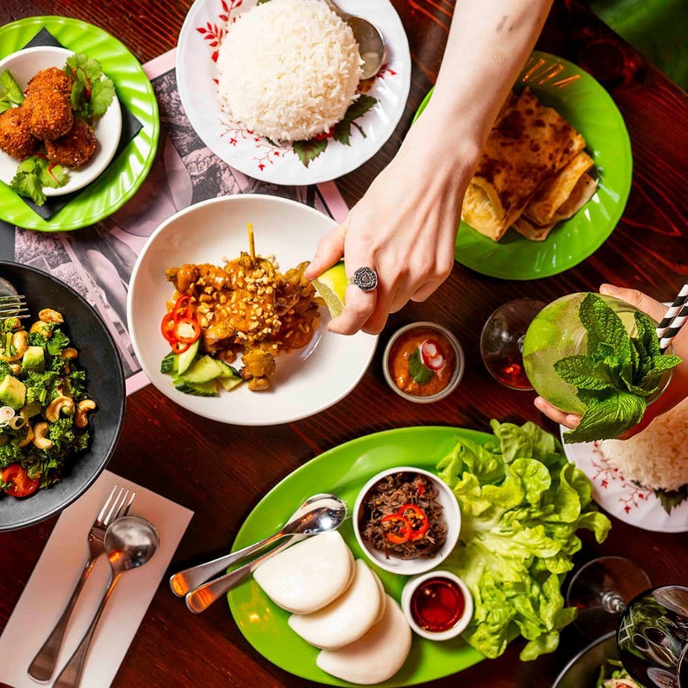 Overhead view of a vibrant Asian feast with various dishes, rice, and fresh vegetables.